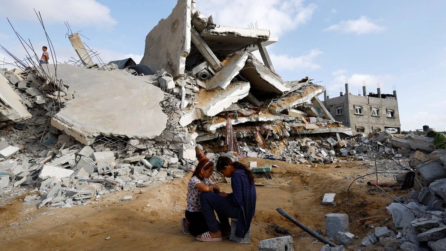 Zwei Mädchen sitzen vor einem durch einen israelischen Luftangriff zerstörten Haus in Rafah (Gazastreifen).