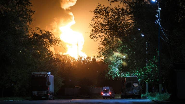 Eine Flamme sticht in den nächtlichen Himmel hinter Bäumen in Luhansk (von Russland besetztes Gebiet in der Ukraine).